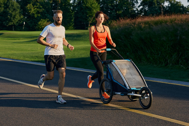 积极的家庭。年轻的家庭和他们的孩子在慢跑婴儿车在公园慢跑图片下载
