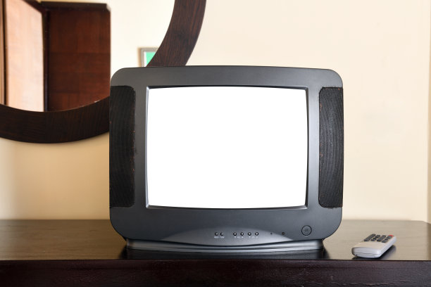 公寓的床头柜上放着一台带有白色屏幕的老式黑色电视，用来添加图像。上世纪80年代、90年代、2000年代的老式电视机。图片下载