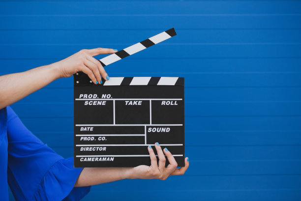 电影制作的拍板由女性手持，背景为蓝色。图片下载