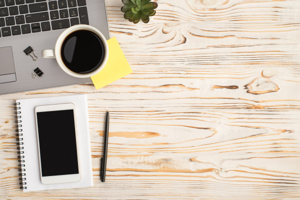 顶视图照片的杯子饮料，活页夹，黄色贴纸笔记笔记本电脑，植物笔和智能手机上的组织者孤立的明亮木桌背景与空白的空间图片下载
