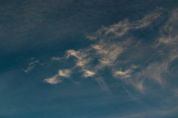 细细的白云被风吹成波浪状，飘浮在点缀着一簇簇白云的蓝天下。图片下载