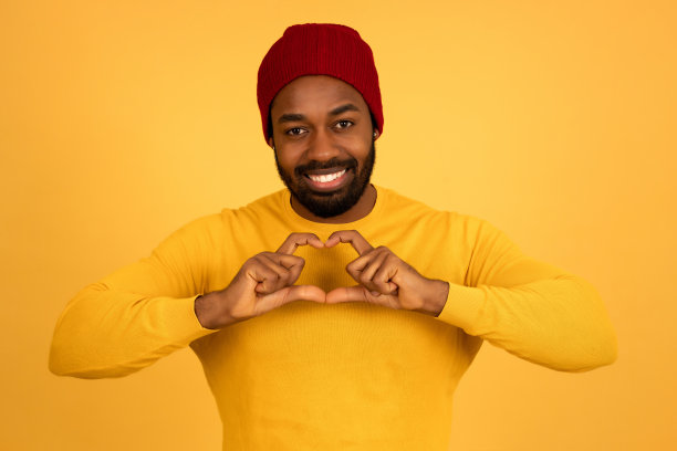 一个非洲男人微笑着用她的手做一颗心。图片下载