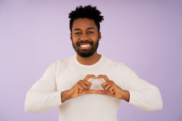 一个非洲男人微笑着用她的手做一颗心。图片下载