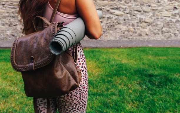 一个背着背包和瑜伽垫的女人从后面过来图片下载