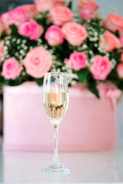 香槟杯的特写图像。新娘一天的梦想。美丽的婚礼细节和装饰，背景是粉红色玫瑰花束图片下载