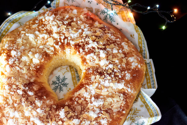 国王蛋糕或黑色背景和圣诞彩灯的Roscon de Reyes。典型的西班牙圣诞甜点。图片下载
