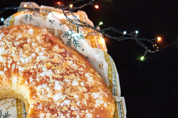 国王蛋糕或黑色背景和圣诞彩灯的Roscon de Reyes。典型的西班牙圣诞甜点。图片下载