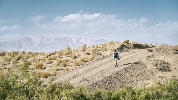 亚洲男女摄影师走在戈壁沙漠的土路上图片下载