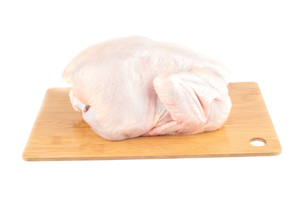 把整只新鲜的鸡放在砧板上，背景是白色的。图片下载