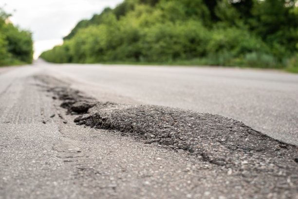 由于超载的卡车在柏油路上行驶，路面出现了巨大的隆起图片下载