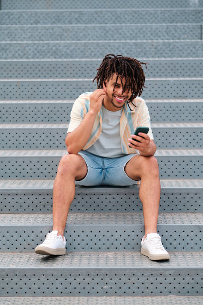拉丁裔卷发男子使用智能手机的垂直照片图片下载