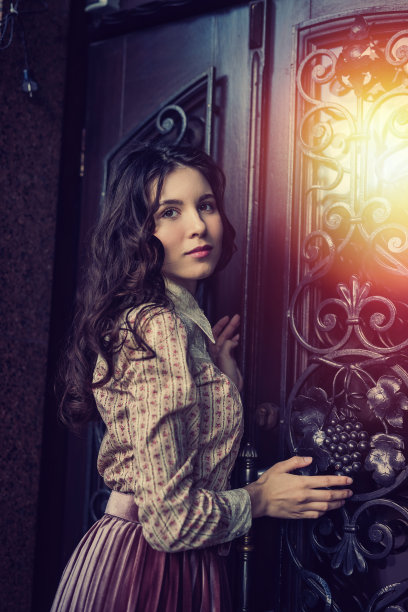 年轻女士的肖像穿着时尚的布料在旧的纹理门附近摆姿势图片下载