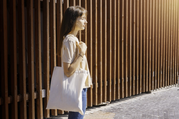 女人拿着白色帆布大手提袋。袋模型设计。图片下载