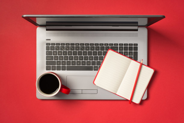 顶视图照片的红杯饮料打开红色的copybook和铅笔在打开的灰色笔记本电脑上孤立的红色背景与copyspace图片下载