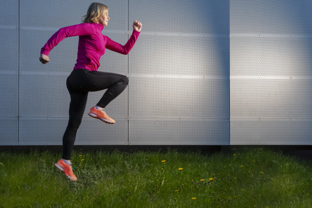 慢跑的概念。对着抽象金属墙进行户外慢跑训练的成熟女运动员。水平的形象图片下载