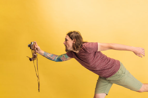 年轻男子的肖像，摄影师，摄影师与复古相机孤立在黄色工作室背景。职业概念，工作，有趣的模因情绪图片下载