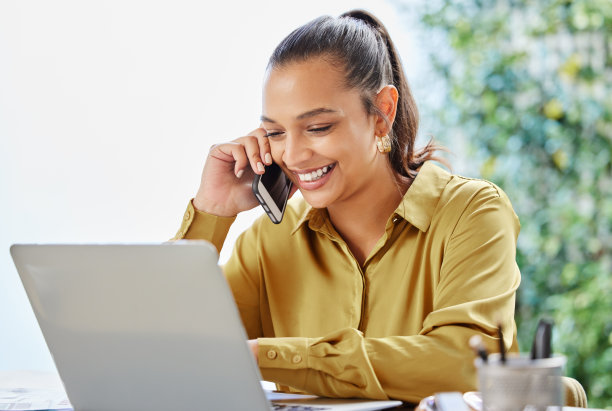 一个漂亮的年轻女商人在家里用笔记本电脑工作时打电话的裁剪照片图片下载