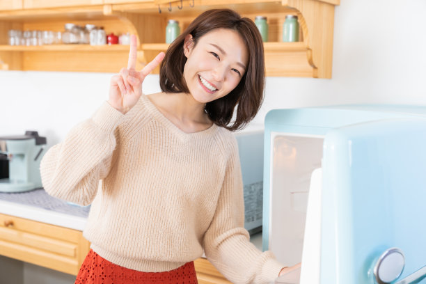 漂亮的亚洲女人在厨房做饭，冰箱图片下载