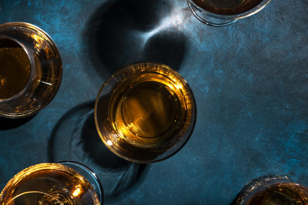 烈性酒、烈性酒、烈性酒和蒸馏酒放在玻璃杯里:干邑白兰地、苏格兰威士忌和其他。蓝色背景，俯视图图片下载
