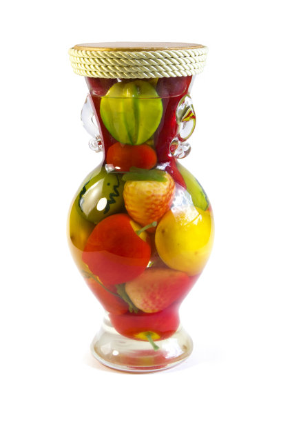 由白色背景上分离的透明玻璃花瓶里的人工水果组成的彩色构图图片下载