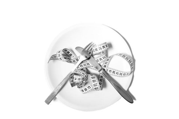 把卷尺放在白色餐盘上，上面放着刀叉。说明健康饮食和节食。孤立在白色背景上。图片下载