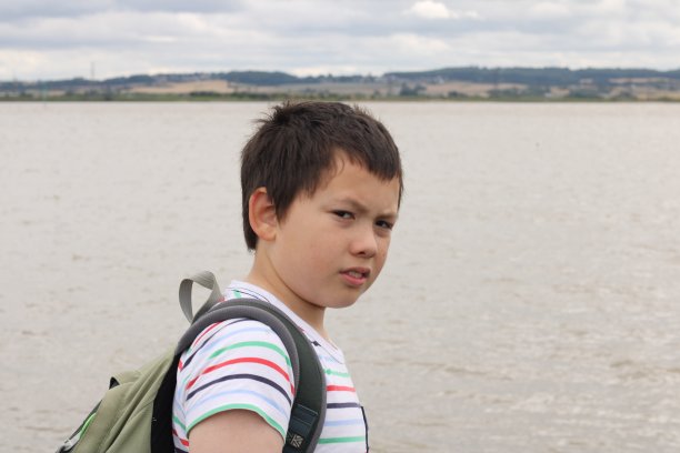 年轻的男孩沿着潮汐的河流散步图片下载