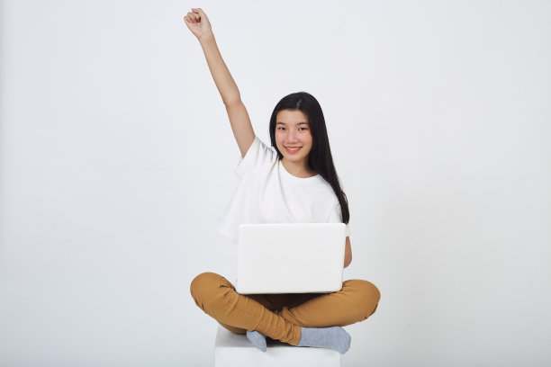 幸福女人的肖像随意坐在地板上，使用笔记本电脑隔离在白色背景图片下载