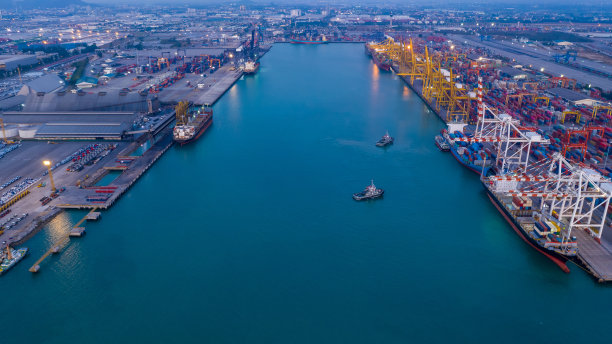 集装箱船舶码头，工业港口集装箱船舶装卸及码头吊用集装箱船舶，货物货物进出口业务物流运输的黄昏鸟瞰图图片下载