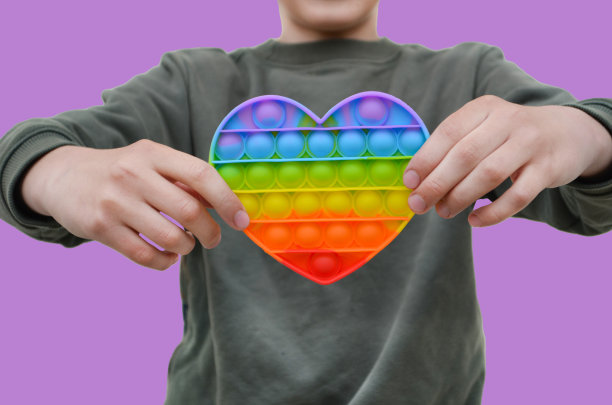 孩子用它pop玩具在手中合上，彩虹硅胶玩具形状心形图片下载