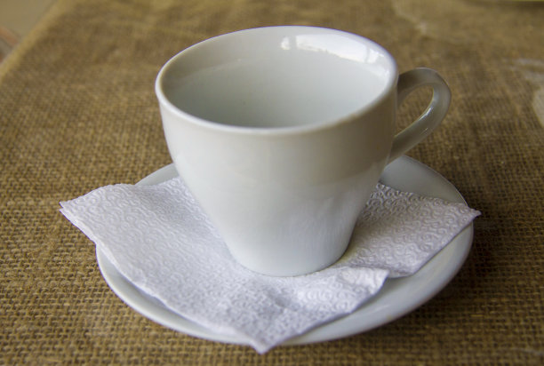壁炉上放着一只白色的空杯子，用来喝热茶，室外的桌子上放着白色的餐巾图片下载