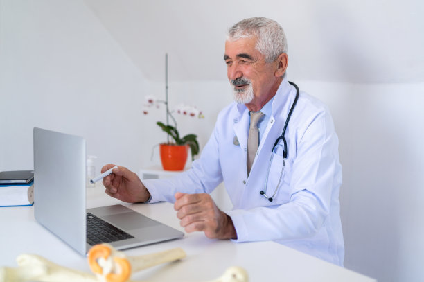 资深医生为他的病人在家庭办公室在线咨询。图片下载