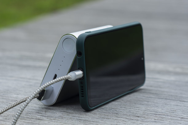 在公园的木凳上为智能手机充电。图片下载