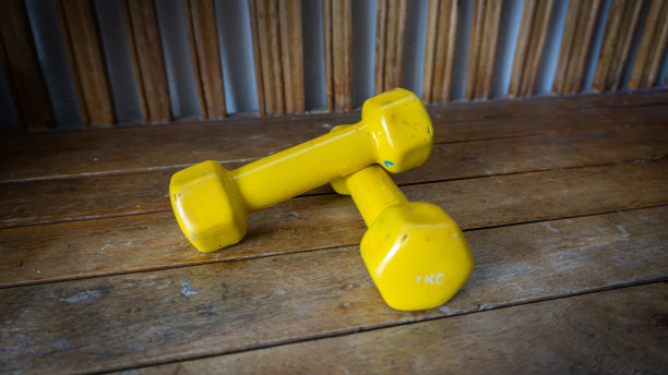近距离观察一对1公斤的黄色迷你哑铃木制背景。图片下载