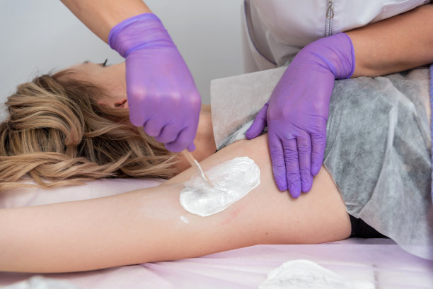 脱毛蜡概念。在水疗沙龙用白色蜡处理腋下女孩脱毛，白色背景。图片下载