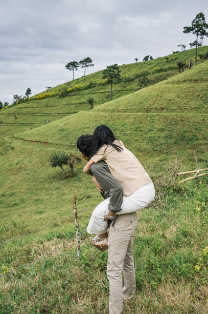 年轻的亚洲夫妇在乡村的草地上骑着马度假图片下载