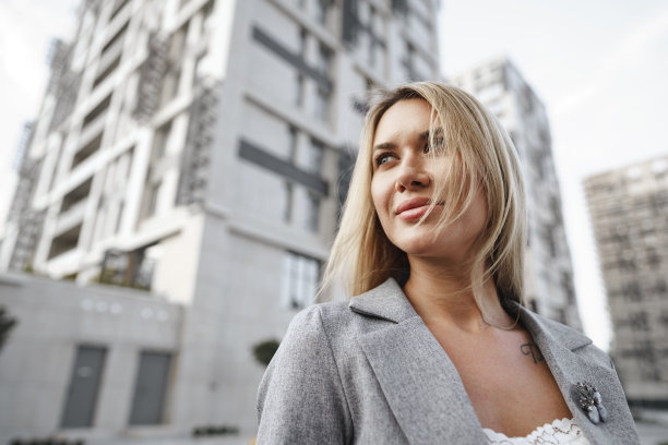 一幅身穿灰色西装的年轻金发女商人在城市里行走的画像图片下载