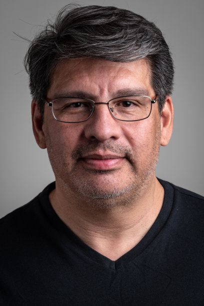 一个成熟的男人微笑着看着灰色背景下的相机图片下载