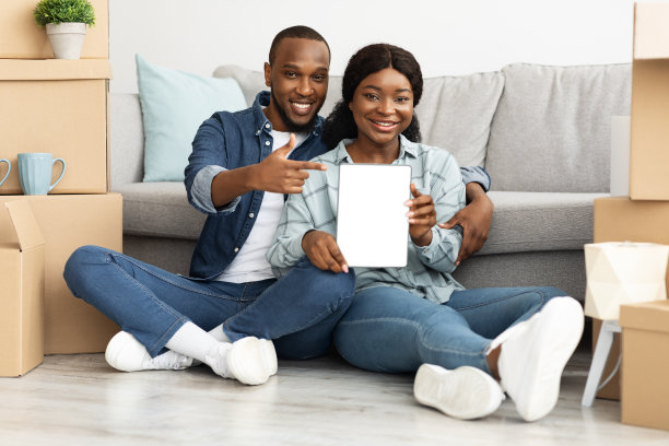 微笑的黑人夫妇在移动后指着黑屏的电子平板电脑图片下载