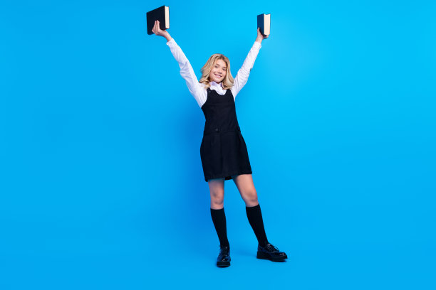 开朗的年轻快乐的女孩手握书籍微笑学校孤立在蓝色的背景照片图片下载