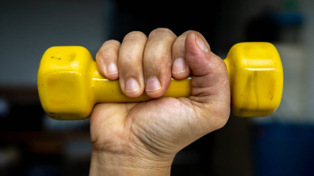 女子手里拿着一个黄色的1公斤轻的迷你哑铃。图片下载