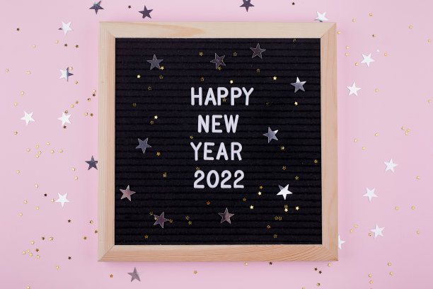 平坦地躺在信板上写着祝贺2022年新年快乐。前视图。节日背景与星星的五彩纸屑图片下载