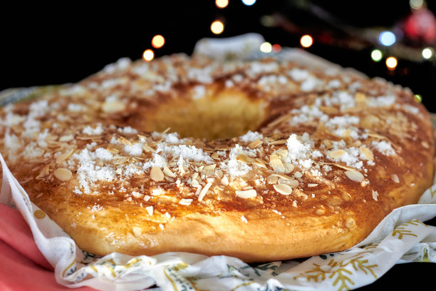 国王蛋糕或黑色背景和圣诞彩灯的Roscon de Reyes。典型的西班牙圣诞甜点。图片下载