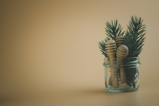 在一个黄色背景的玻璃罐里装着一根木蜂蜜棒图片下载