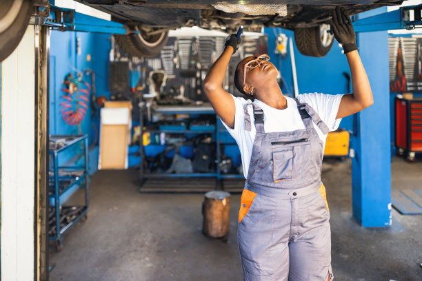 一名黑人女性技工在汽车服务车辆下工作的肖像照片。图片下载