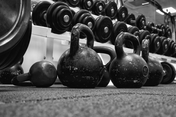 把杠铃和壶铃放在橡胶地板上，准备进行力量和体能训练。图片下载