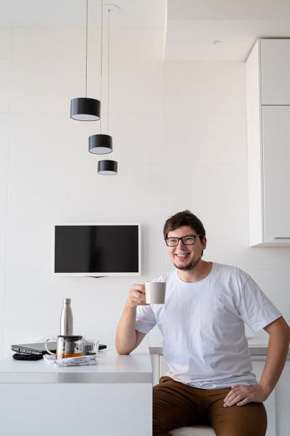 一个快乐的年轻人在家里享用早餐，思考着图片下载