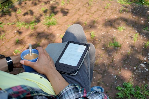 一名女子拿着带有电子墨水屏幕的阅读器阅读电子书图片下载