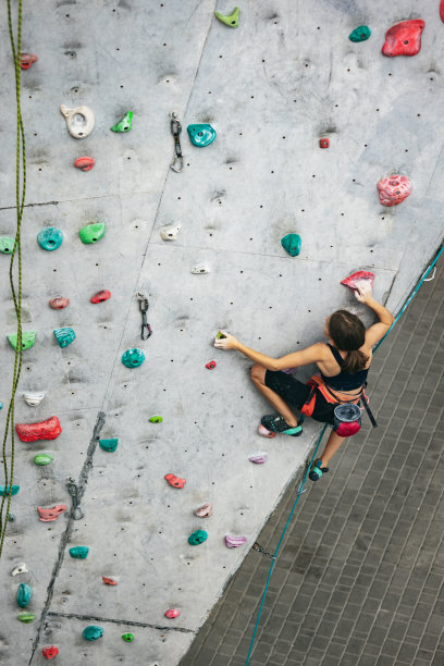 一个可爱的少女在攀岩中心的岩壁上练习。运动的生活方式，活动的概念，快乐的童年图片下载