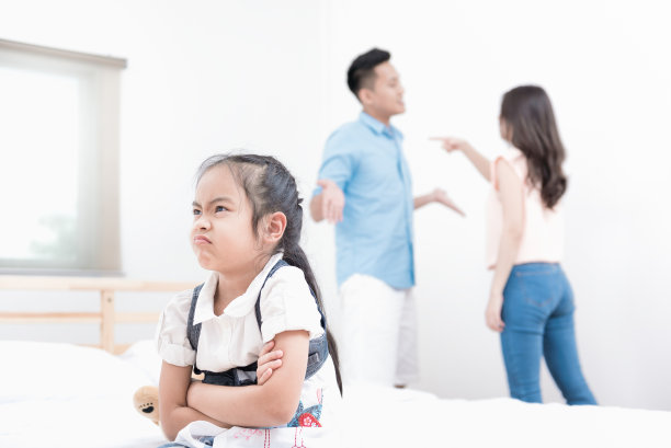 坐在家里的床上不高兴的可爱小女孩，因父母争吵而生气地交叉双臂，家庭冲突图片下载