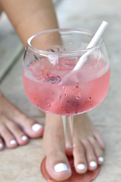 女孩的脚拿着玻璃杯粉红色的饮料图片下载